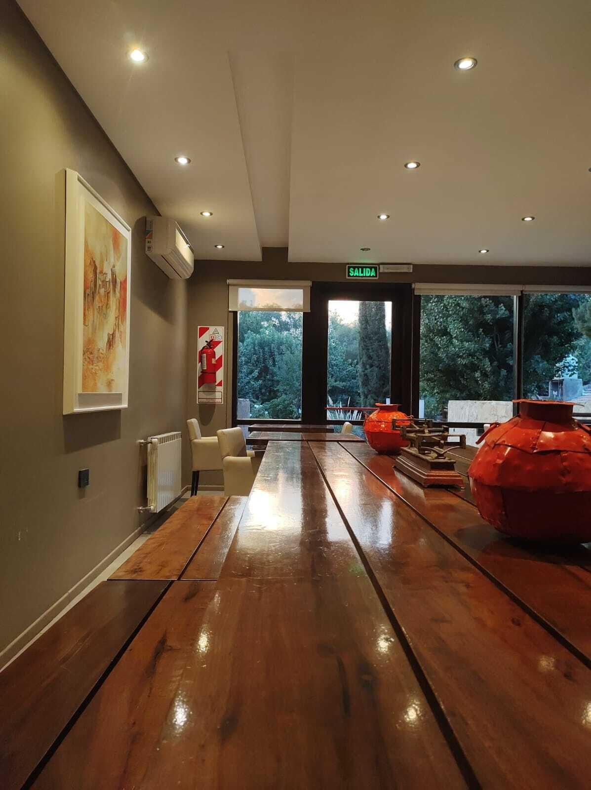 A spacious lobby with a wooden floor, a large window with a view of trees, and a sign indicating the exit.