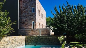 Una piscina con paredes de piedra y un edificio moderno al fondo.