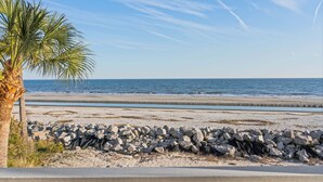 A beach with a palm tree and a rocky shoreline. - Oceanfront retreat, step onto the beach and a short distance to the Pier Village (Saint Simons Island)