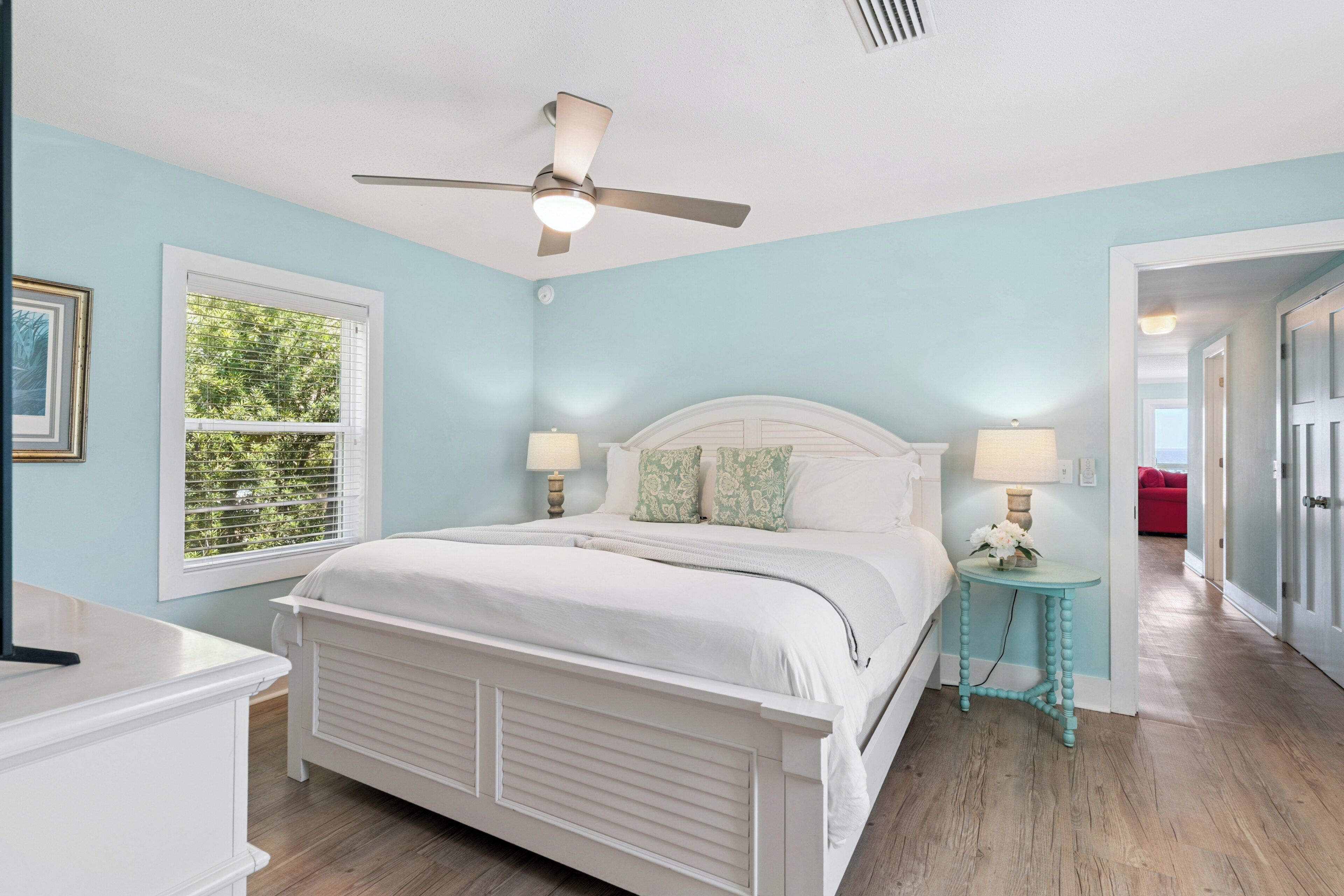 A bedroom with a bed, bedside tables, a ceiling fan, and a window with blinds.