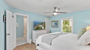 A bedroom with a bed, a dresser, a television, and a window with blinds. - Oceanfront retreat, step onto the beach and a short distance to the Pier Village (Saint Simons Island)