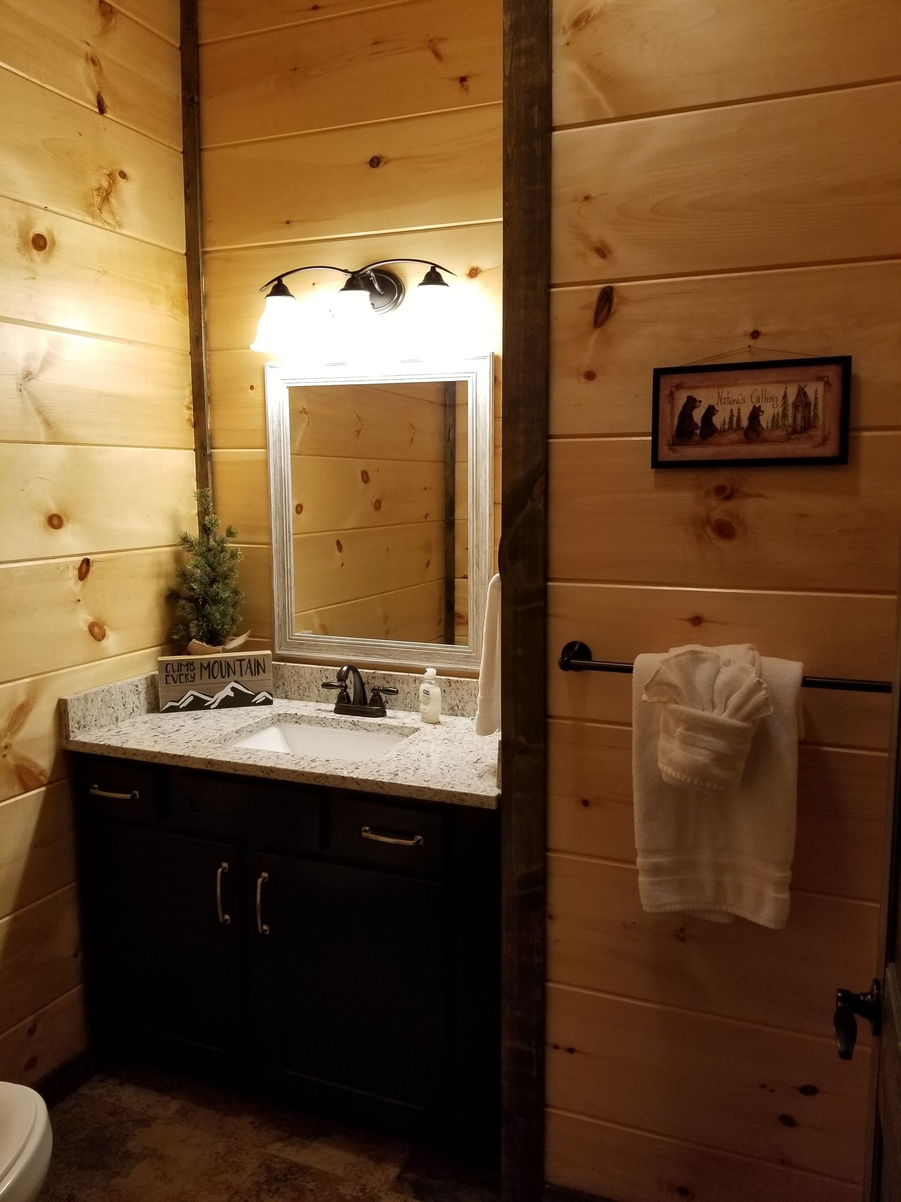 Een houten badkamer met een granieten aanrecht, een wastafel, een spiegel en een handdoekhouder.