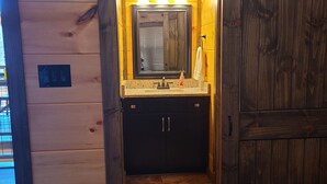 Een houten cabinneerinterieur met een badkamer, inclusief een wastafel en spiegel.