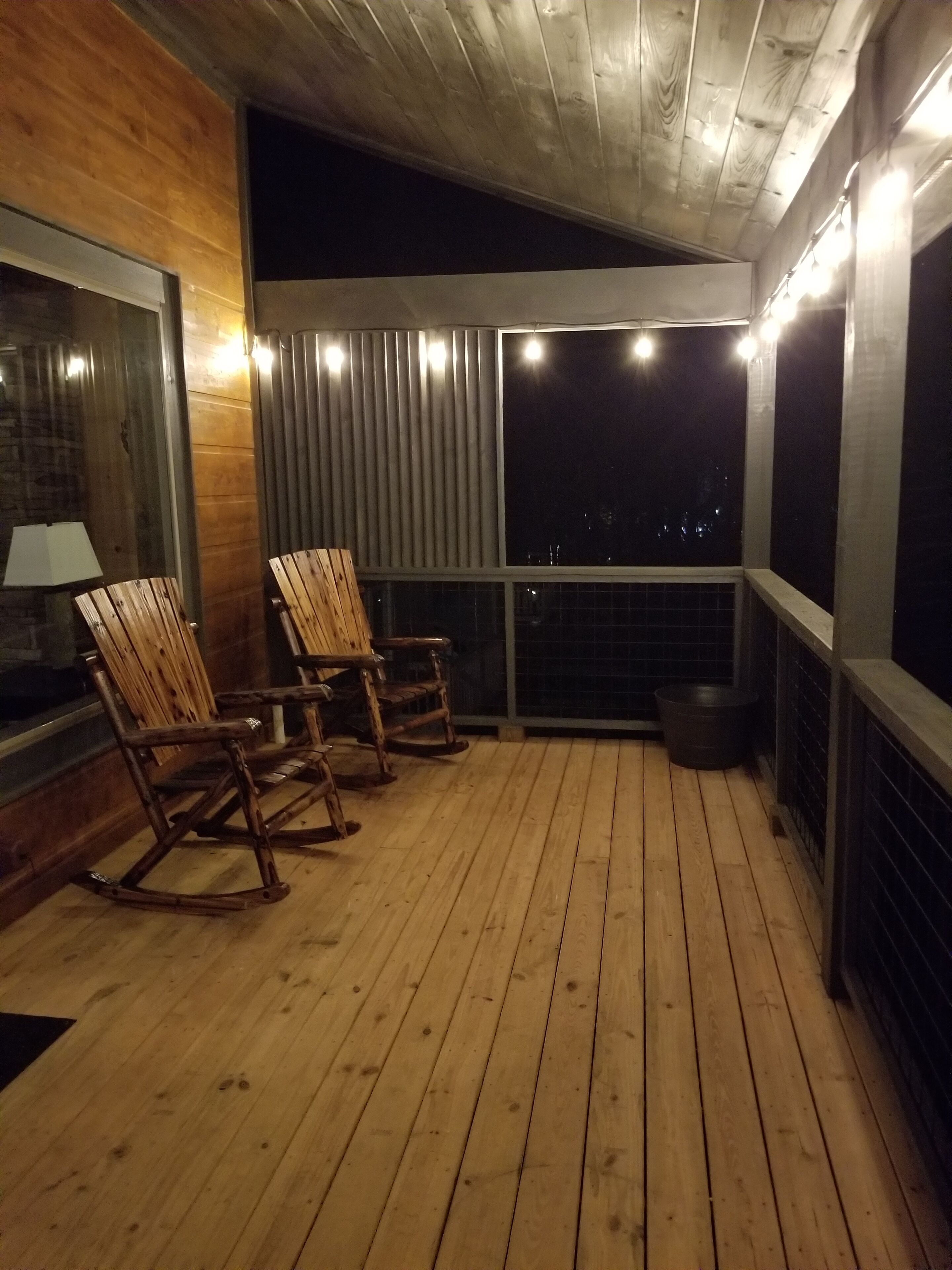 A wooden deck with rocking chairs and a view of the night sky.