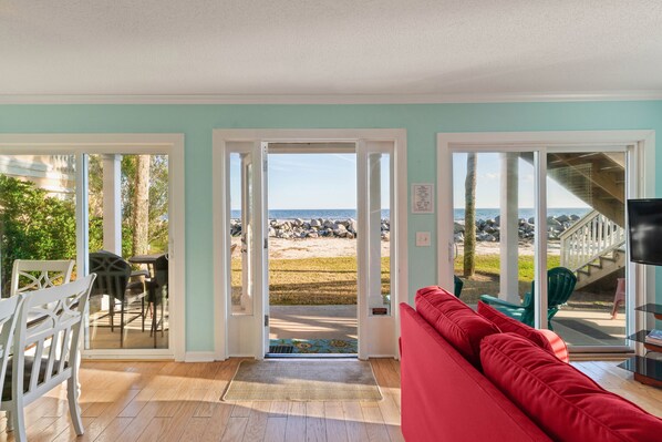 Enjoy a beachside retreat with a sofa, dining table, and TV, plus access to an outdoor area via a staircase.