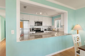 Enjoy cooking in this well-equipped kitchen with a central island, refrigerator, microwave, and oven.