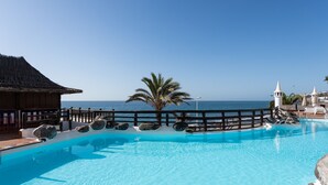 A clear blue pool with a wooden deck, a palm tree, and a view of the sea. - Altamar 52 with balcony&pool By CanariasGetaway (San Bartolomé de Tirajana)