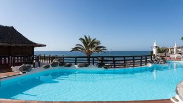 Une piscine d’un bleu éclatant, dotée d’une terrasse en bois et offrant une vue sur la mer.