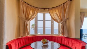 A curved red bench with a round table in front, a window with beige curtains, and a view of the sea. - Altamar 52 with balcony&pool By CanariasGetaway (San Bartolomé de Tirajana)