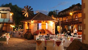 Un hotel rústico con un molino, zona de comedor al aire libre y una escalera que conduce al piso superior.