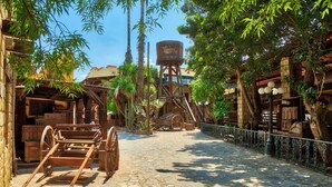 Un camino empedrado que lleva a un edificio rústico con construcciones de madera y una torre de agua.