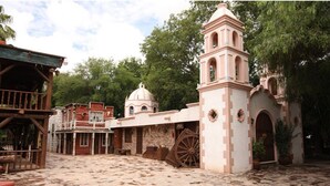 Un edificio histórico con una torre de campanas, una cúpula y una gran rueda de madera.