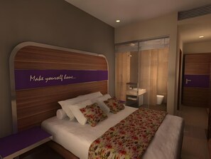 A modern bedroom with a wooden headboard, a bed with floral bedding, a bench, and a bathroom visible through a glass partition. - Cititel Hotel Dumai (Dumai)