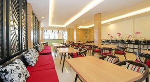 A restaurant with red seating, wooden tables, and black chairs. - Cititel Hotel Dumai (Dumai)