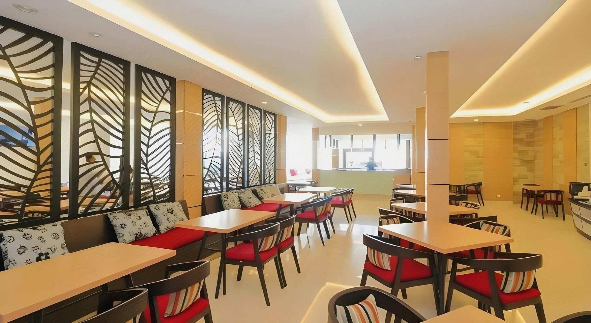 A modern restaurant with multiple seating areas, including booths and tables, and a visible kitchen area in the background.