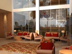 A spacious lobby with modern furniture, large windows, and a decorative wall feature.