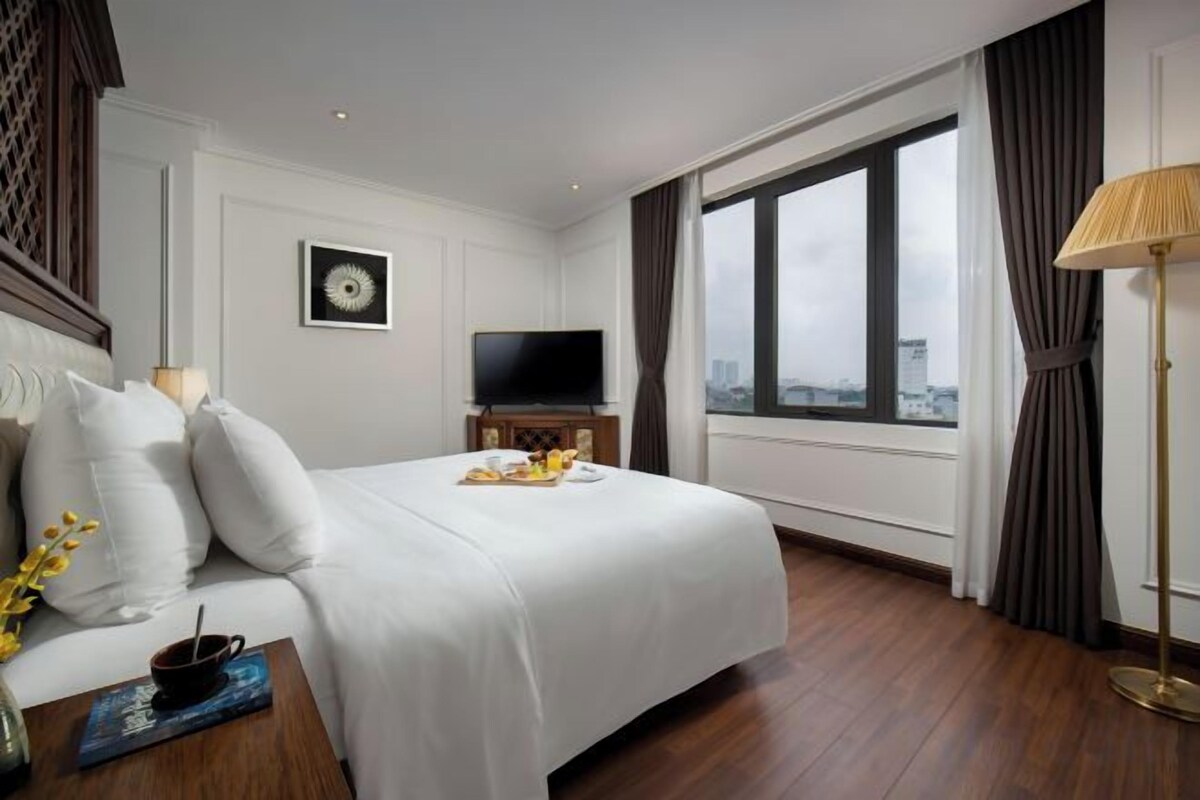 Une chambre d’hôtel avec un grand lit, une télévision, une fenêtre avec des rideaux et une vue sur la ville.