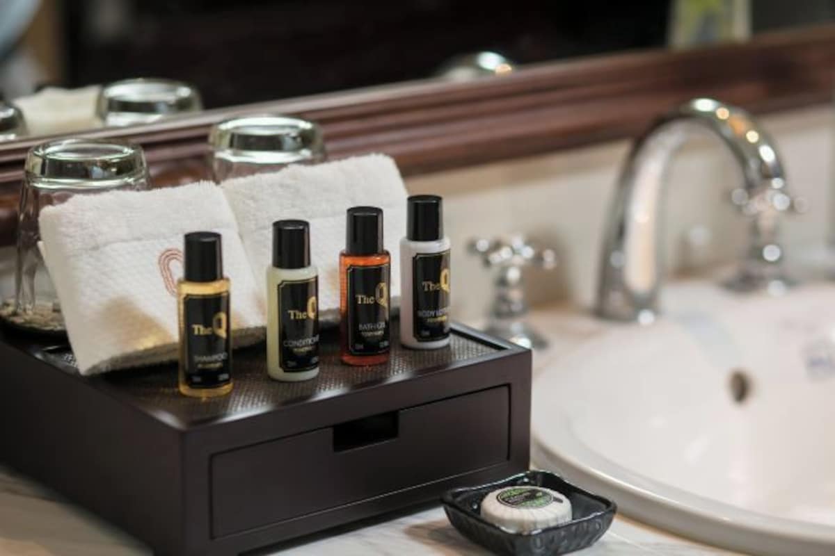 Un tocador de baño con una bandeja de madera oscura que contiene varios artículos de aseo, una toalla blanca y un pequeño recipiente con jabón.