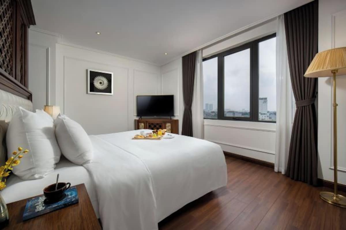 Una habitación de hotel con una cama grande, televisor de pantalla plana, vista a la ciudad y una decoración moderna.