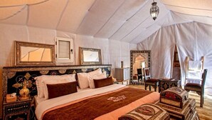 Ein Zeltraum mit einem großen Bett, einem verzierten Kopfteil und einer Kristallleuchtre.