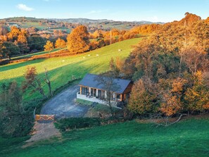 Uma cabana isolada com varanda e vista para um campo verde e árvores.