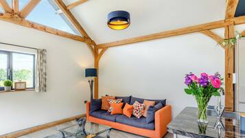 A cozy living room with a sofa, a glass coffee table, and a pendant light.