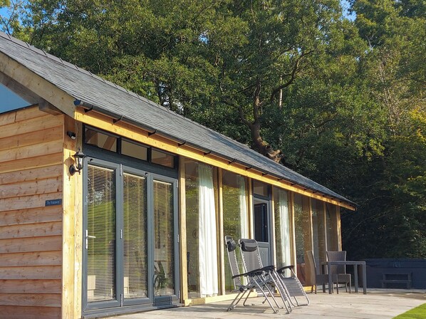 A wooden cabin with large sliding glass doors, a covered patio with outdoor furniture, and a sign reading "The Hideaway".