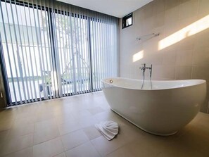 A modern bathroom with a freestanding bathtub, large windows with blinds, and a tiled floor. - Paradise Beach Resort (Ban Chang)