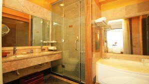 Une salle de bain avec un meuble-lavabo en marbre, une douche à parois de verre et une baignoire blanche.