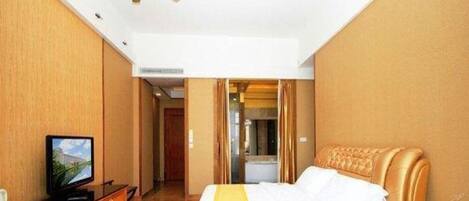 A hotel room with a bed, a television, a desk, and a ceiling fan.