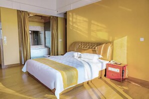 Habitació d'hotel amb un llit gran, una nitriera vermella i un bany visible darrere d'una cortina.