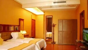 Une chambre d’hôtel avec deux lits, une télévision, une armoire et un miroir.
