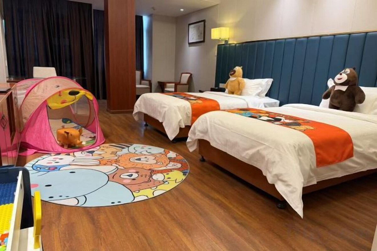 A hotel room with two beds, a play tent, and a colorful rug.