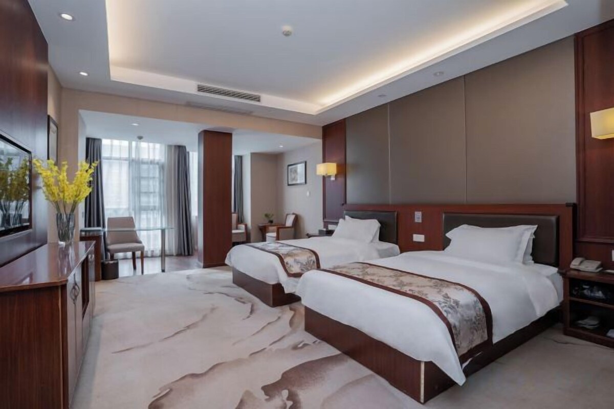 Una habitación de hotel con una cama grande, un escritorio, una silla y un televisor.