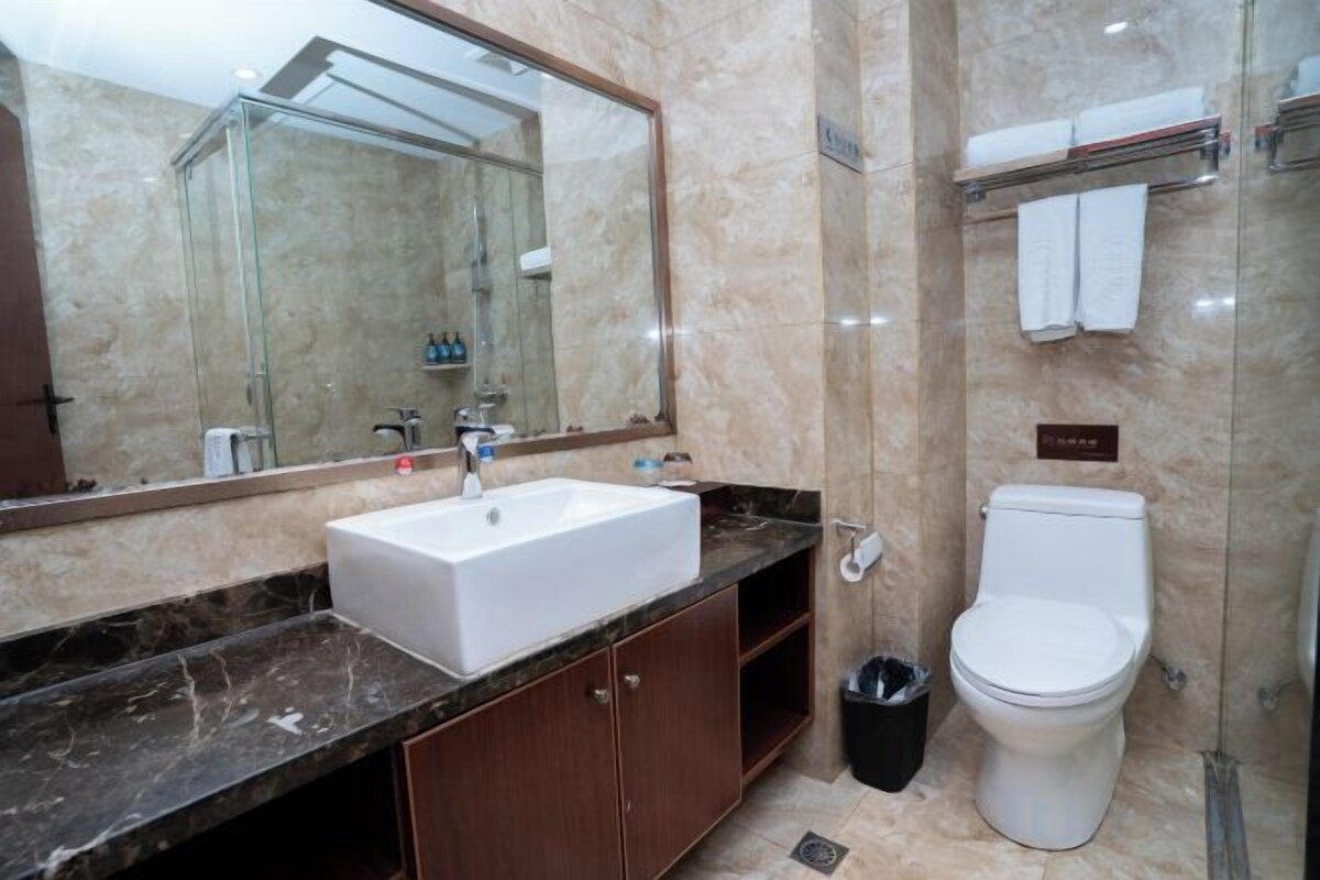 Un baño con lavamanos de mármol, inodoro y cabina de ducha de vidrio.