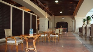 A spacious lobby with a high ceiling, tiled floor, and a seating area with wicker chairs and tables. - Grand Metropark Longxi Conference Center Beijing (Daxing)
