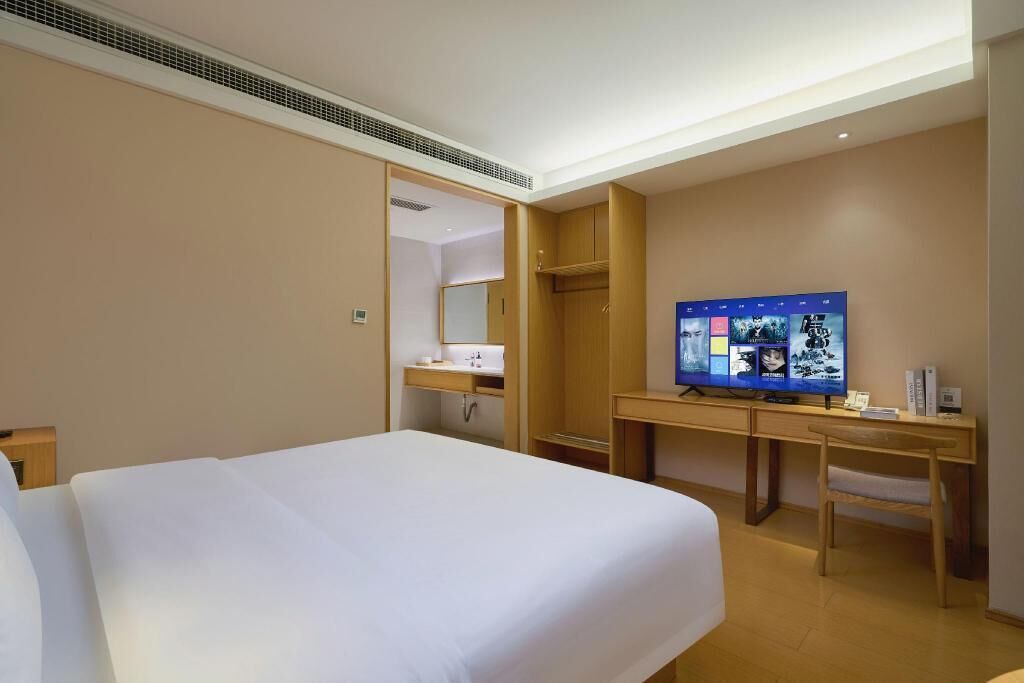 Ett hotellrum med en säng, ett skrivbord, en tv och en garderob.