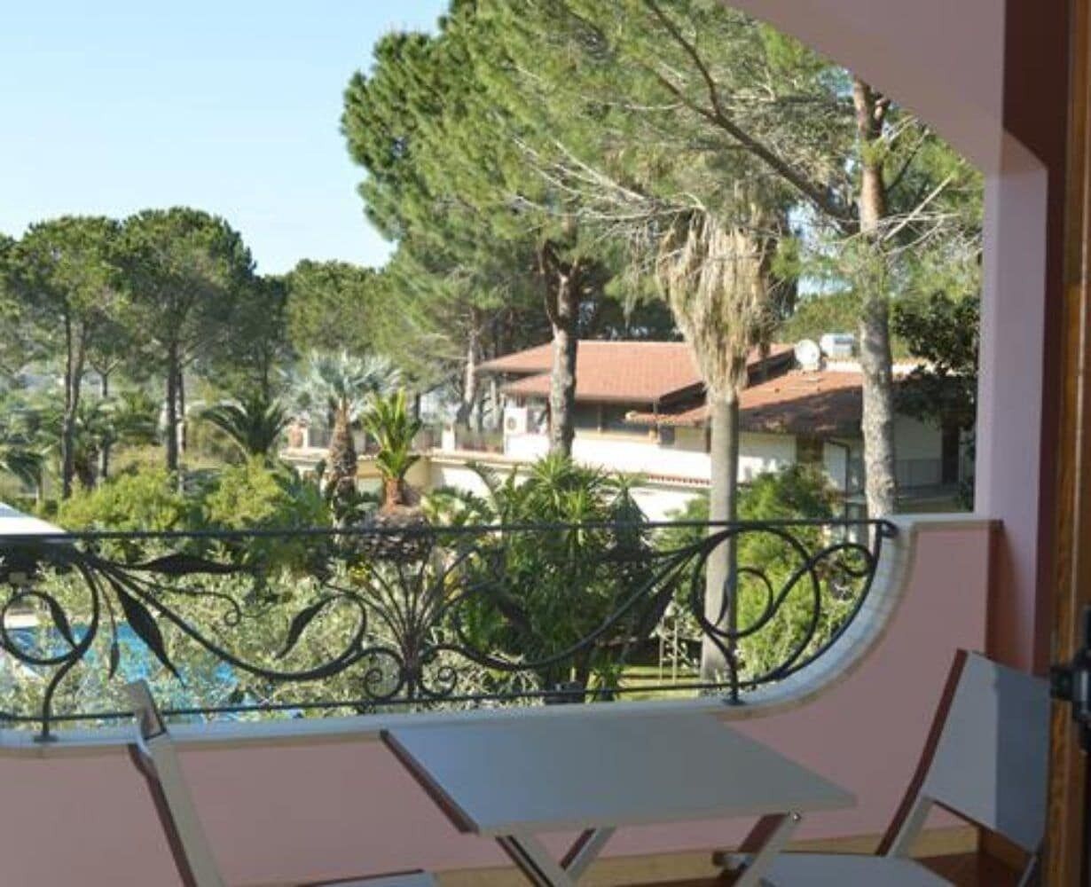 A balcony with a view of a residential area, including houses and trees.