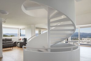 A modern interior with a spiral staircase, a sofa, and a view of the outdoors.