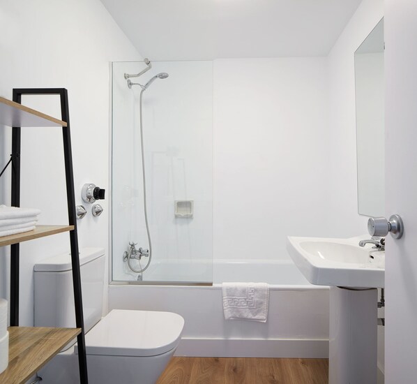 A modern bathroom with a glass-enclosed shower, a white sink, and a toilet.