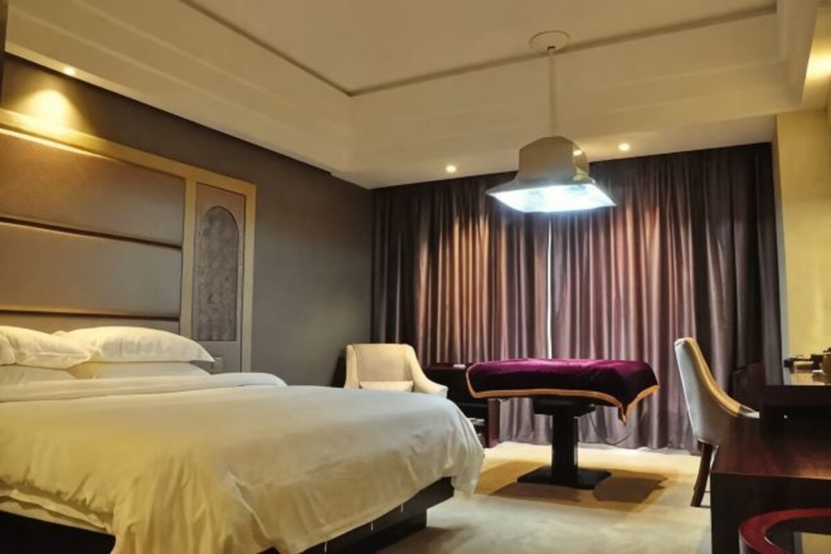 Una habitación de hotel con una cama grande, un escritorio, una silla y una lámpara de escritorio.