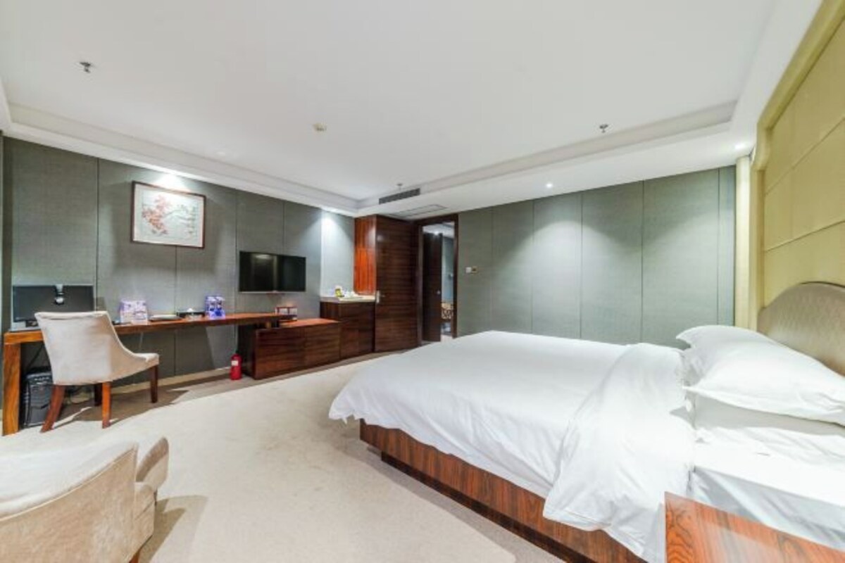 Una habitación de hotel moderna con una cama grande, un escritorio, una silla y una televisión.