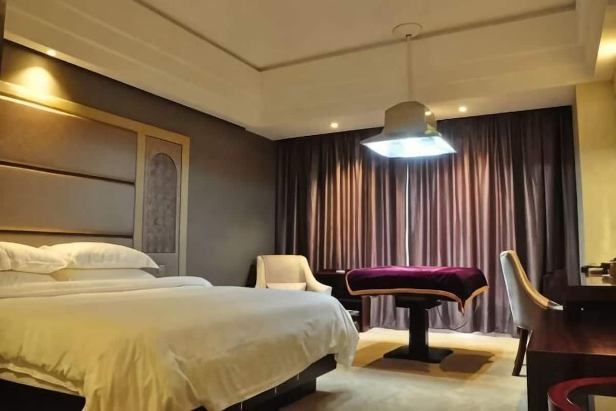 Une chambre d’hôtel avec un grand lit, un bureau, une chaise et une lampe de bureau.