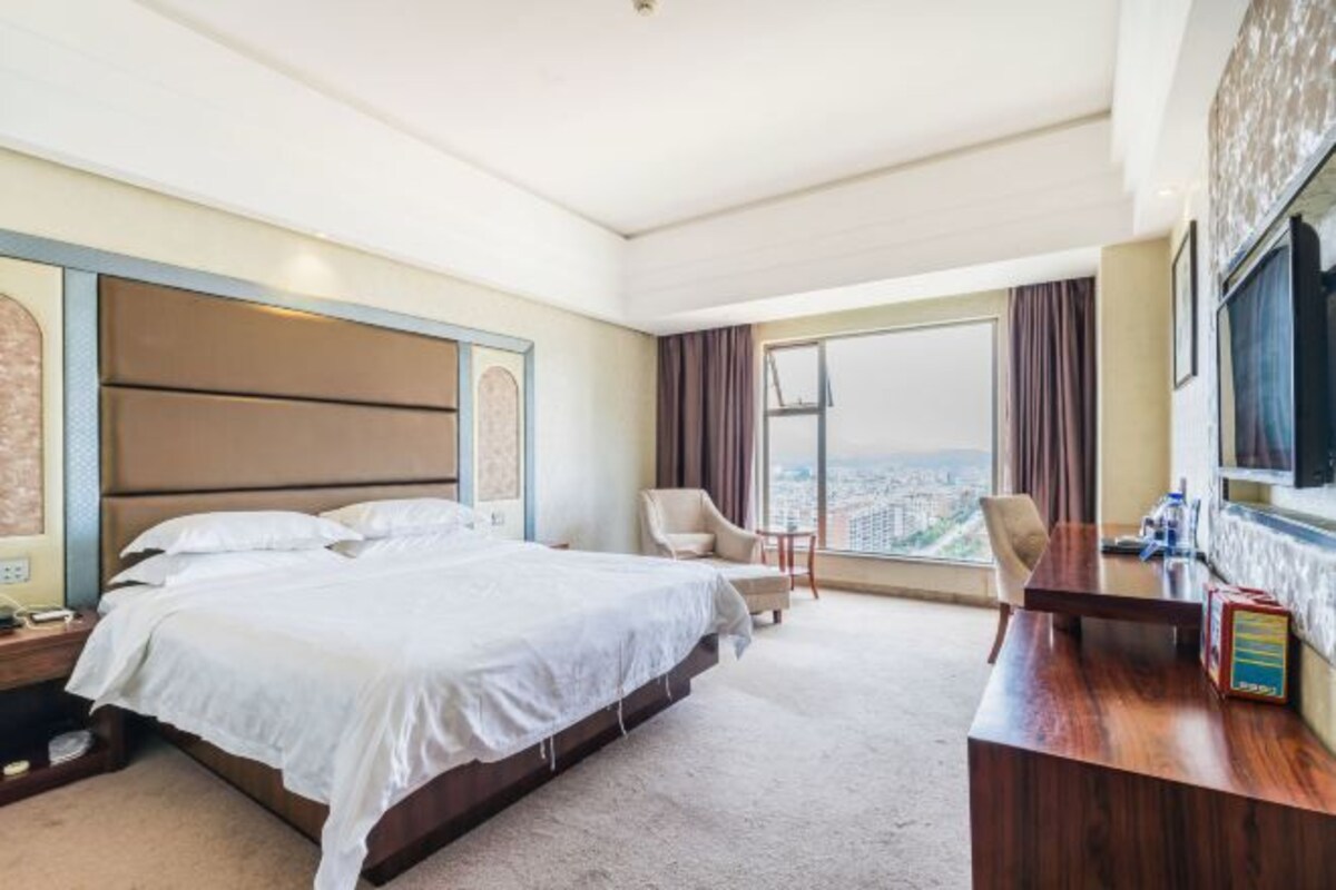 Una habitación de hotel con una cama grande, un escritorio y vistas a la ciudad.