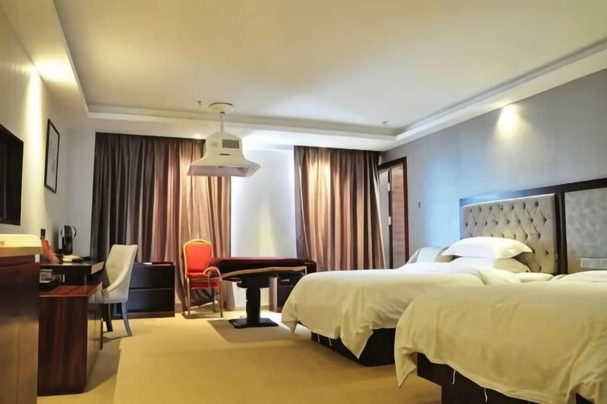 Une chambre d’hôtel avec deux lits, un bureau, une chaise, une table et un téléviseur.