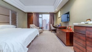 A hotel room with a bed, a desk, a chair, a TV, and a view of the city. - Jiuzhou International Hotel (Yangxi)