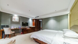 A modern hotel room with a large bed, a desk, a chair, and a television. - Jiuzhou International Hotel (Yangxi)