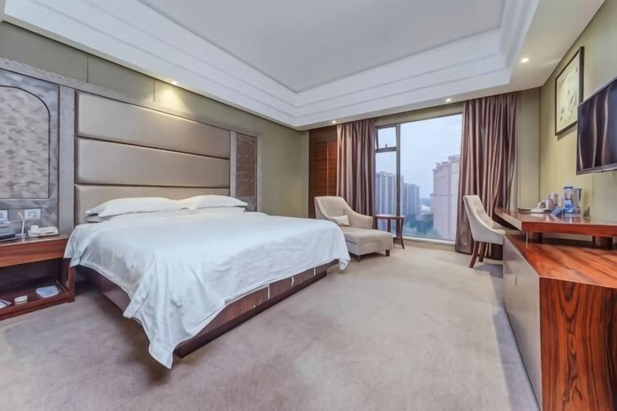 Une chambre d’hôtel avec un grand lit, un bureau, une chaise et une vue sur la ville.