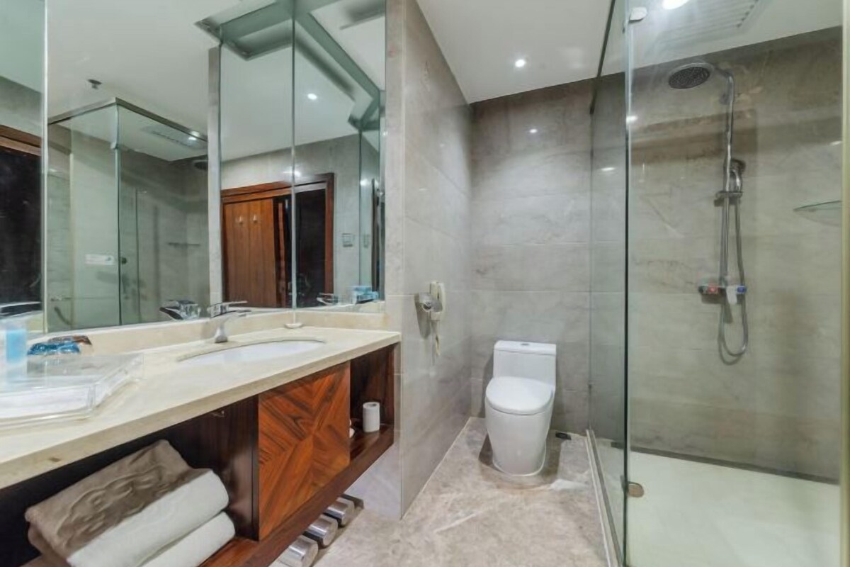 Un baño moderno con cabina de ducha de vidrio, inodoro blanco y tocador con espejo.