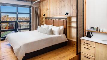A bedroom with a large bed, wooden headboard, and a white bedside table with a kettle.
